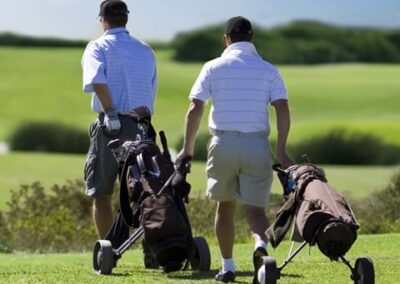 Picture of two male golfers walking with trundlers down the fairway