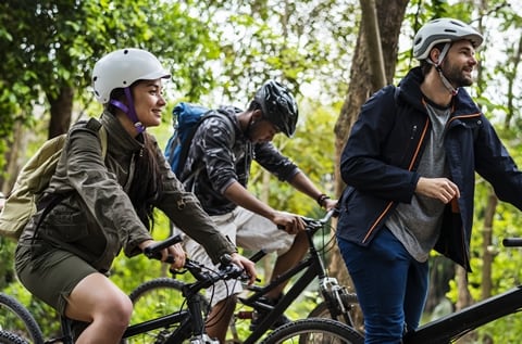 Picture of three cyclists with helmets in a forest setting