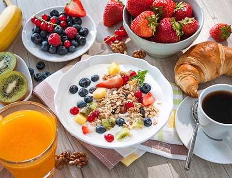 Yogurt with muesli and fresh fruits A fresh and abundant breakfast outdoors with croissants, berries, and coffee, perfect for an autumn escape.