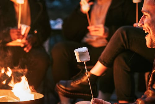 Friends enjoying s'mores and marshmellow together by the bonfire Fire pit with marshmallows at Treghan Lodge – Bay of Islands winter retreat