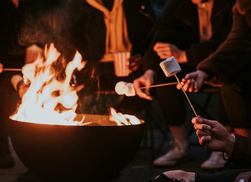 Friends enjoying s'mores and marshmellow together by the bonfire Friends enjoying s'mores and marshmellow together by the bonfire