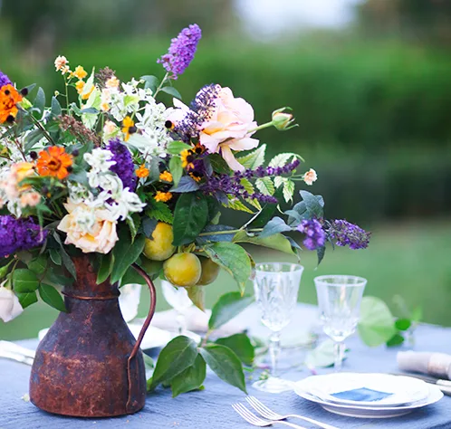 Bouquet of pink, violet and yellow flowers on a table set for dinner
