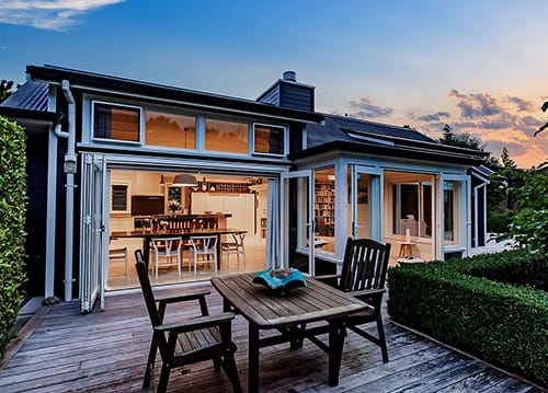 Treghan Lodge at dusk with warm lights glowing inside and doors opening onto a private deck