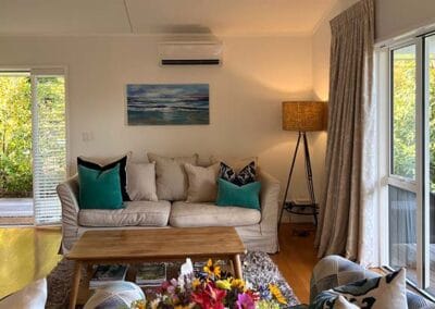 Light-filled guesthouse living area with sofa and doors opening to the garden at Treghan Lodge in Kerikeri, Bay of Islands