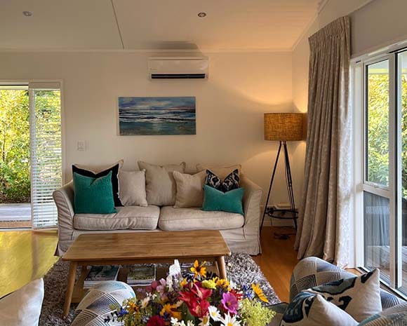 Light-filled guesthouse living area with sofa and doors opening to the garden at Treghan Lodge in Kerikeri, Bay of Islands