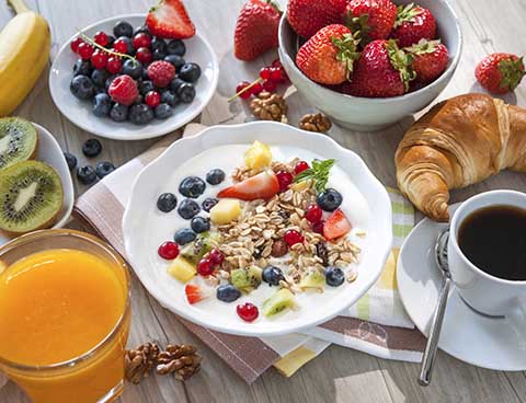 A fresh and abundant breakfast outdoors with croissants, berries, and coffee, perfect for an autumn escape.