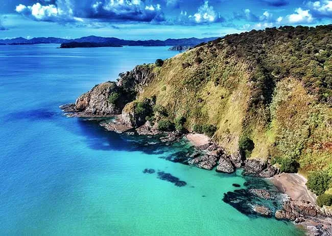 Coastal view of the Bay of Islands with rugged headland, clear turquoise water and secluded shoreline