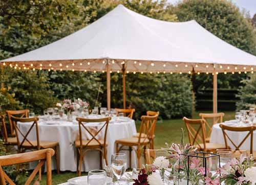Intimate garden wedding ceremony set on Treghan lawn with a sailcloth marquee, surrounded by mature gardens and seating for wedding guests.