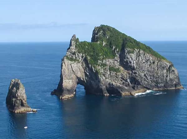 Helicopter approaching the Hole in the Rock at Cape Brett, Bay of Islands
